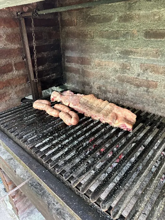 Asado cocinándose en la parrilla de Cabaña Cactus I